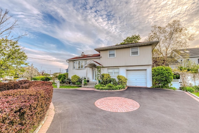 view of front of property featuring aphalt driveway, an attached garage, fence, and a chimney