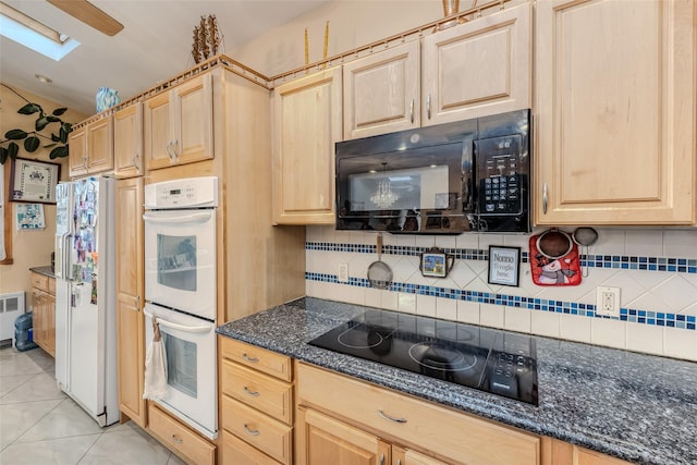 kitchen featuring light tile patterned floors, light brown cabinets, radiator heating unit, decorative backsplash, and black appliances