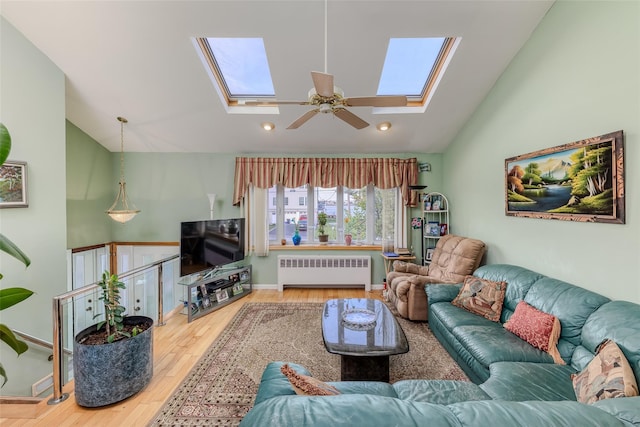 living area with recessed lighting, vaulted ceiling with skylight, radiator, and wood finished floors