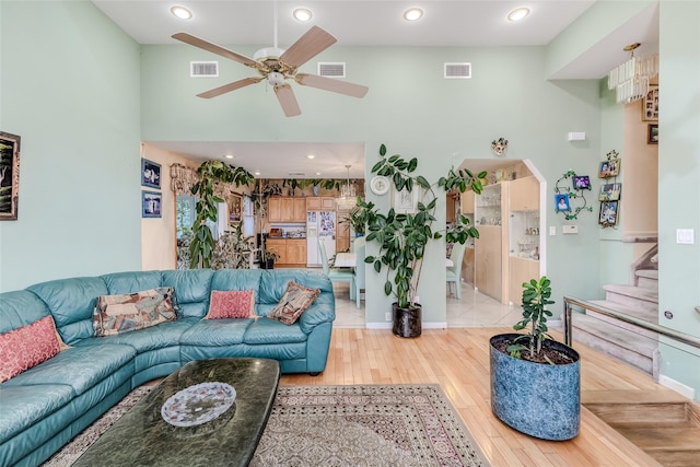 living room featuring visible vents, stairs, ceiling fan, and wood finished floors