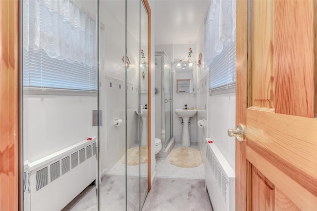 bathroom featuring toilet, radiator, tile walls, and a stall shower