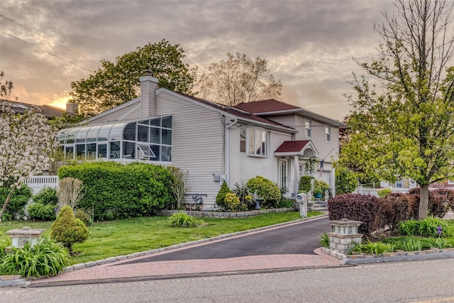 view of front of property with stucco siding, a chimney, and a front lawn