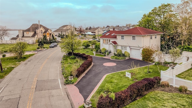 surrounding community featuring aphalt driveway, a residential view, an attached garage, and fence