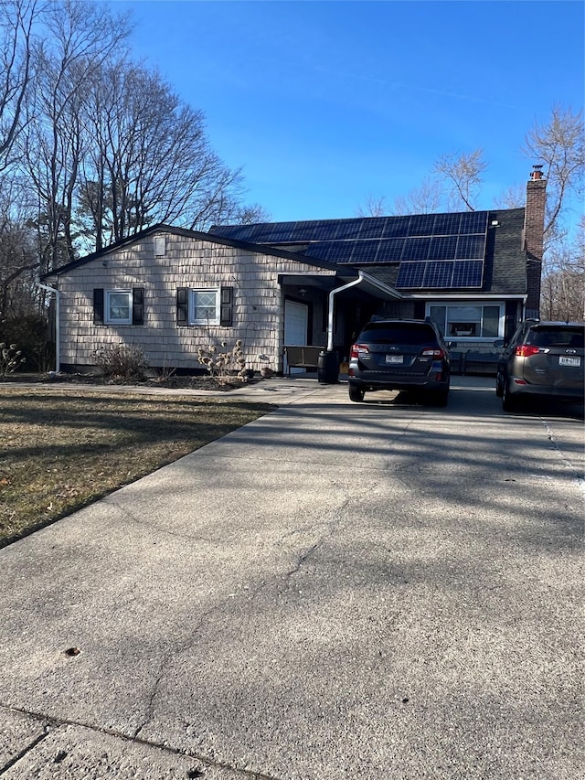 view of front of property featuring roof mounted solar panels and driveway