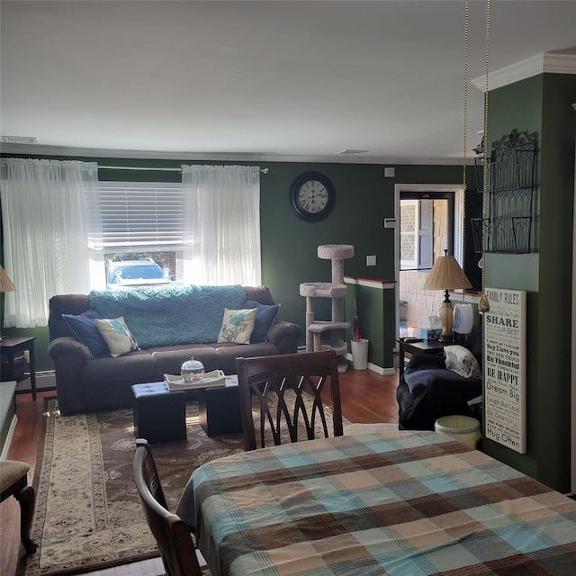 dining room featuring plenty of natural light, a baseboard heating unit, baseboards, and wood finished floors