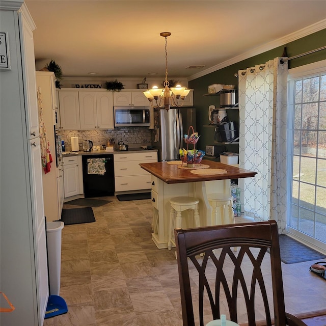 kitchen with wooden counters, ornamental molding, decorative backsplash, appliances with stainless steel finishes, and an inviting chandelier