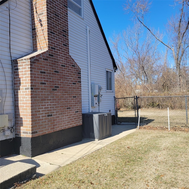 view of side of home featuring a gate, fence, and a lawn