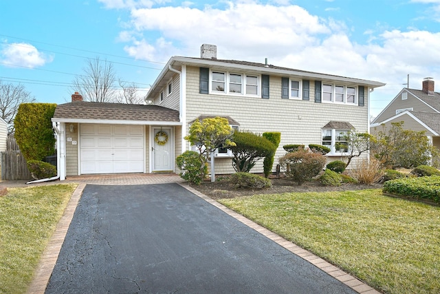 view of front of property with aphalt driveway, roof with shingles, a front yard, an attached garage, and a chimney