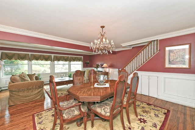 dining room featuring crown molding, a chandelier, a wainscoted wall, stairs, and wood finished floors