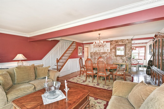 living room with crown molding, stairway, a wainscoted wall, an inviting chandelier, and wood finished floors