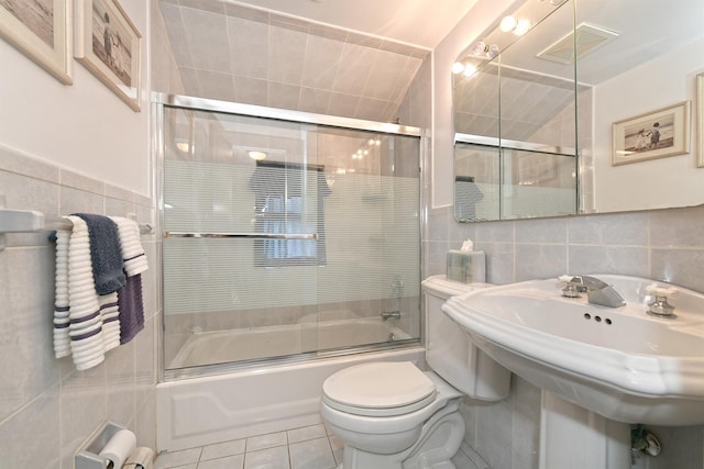 full bath featuring tile walls, toilet, combined bath / shower with glass door, and tile patterned floors