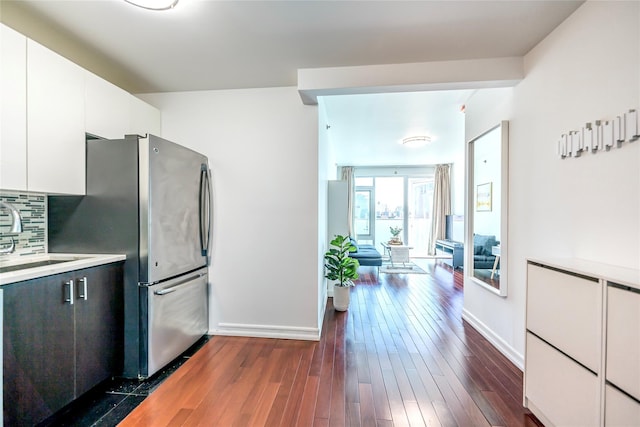 kitchen featuring dark wood-type flooring, white cabinetry, freestanding refrigerator, light countertops, and decorative backsplash