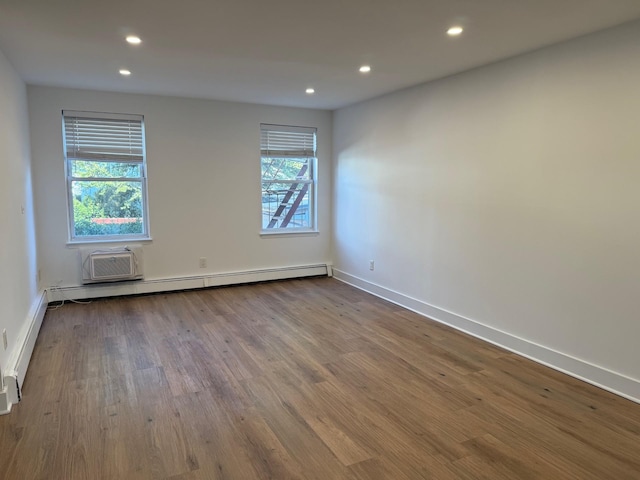 empty room featuring recessed lighting, a baseboard radiator, baseboards, and wood finished floors