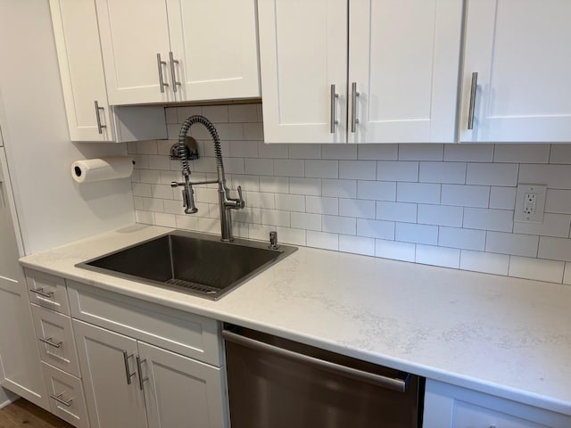 kitchen featuring a sink, light stone counters, tasteful backsplash, white cabinets, and dishwasher