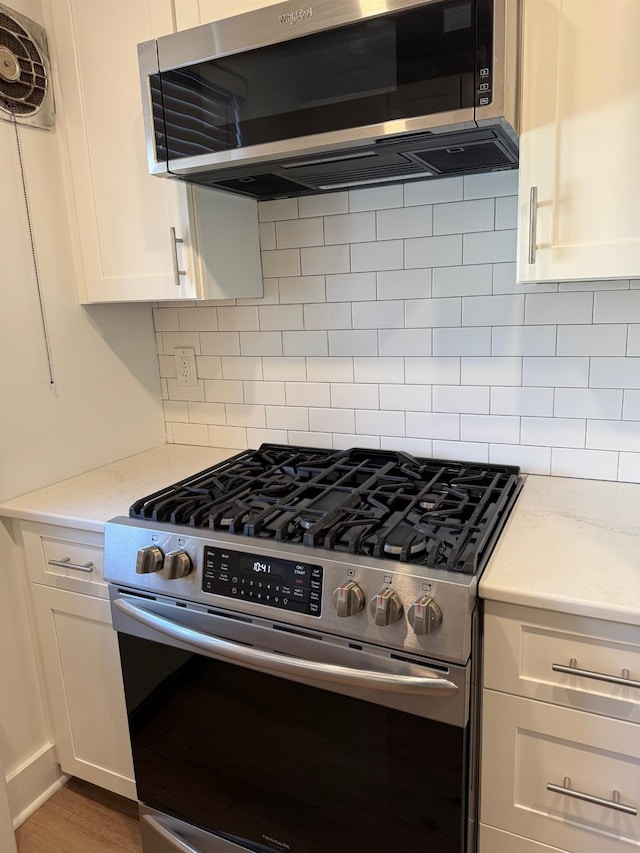 kitchen with decorative backsplash, light stone countertops, appliances with stainless steel finishes, and white cabinets