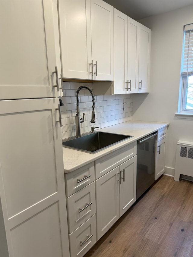 kitchen featuring a sink, tasteful backsplash, white cabinetry, radiator, and dishwasher