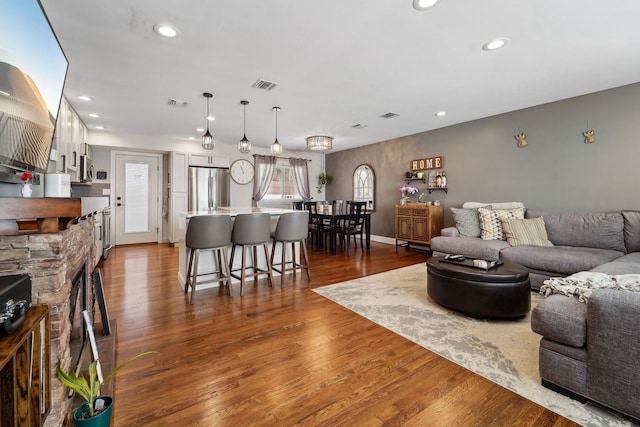 living area with recessed lighting, visible vents, and dark wood finished floors