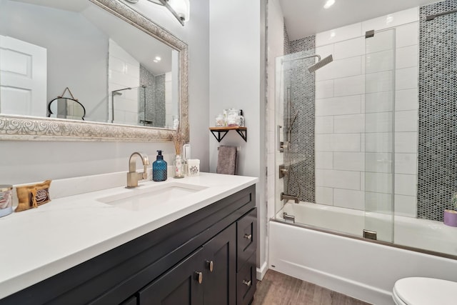 full bath with vanity, toilet, wood finished floors, and combined bath / shower with glass door