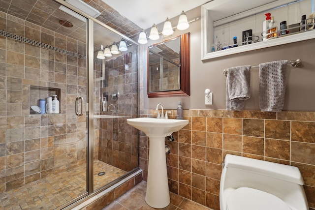 bathroom with tile walls, tile patterned floors, a shower stall, and wainscoting