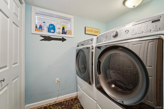 washroom featuring baseboards, separate washer and dryer, and laundry area