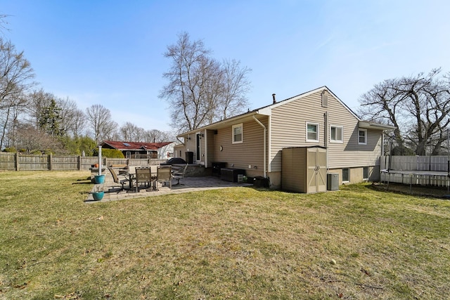 rear view of house featuring a fenced backyard, a lawn, cooling unit, and a patio