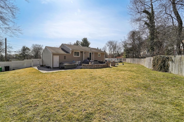 back of house featuring a fenced backyard, a lawn, and a hot tub