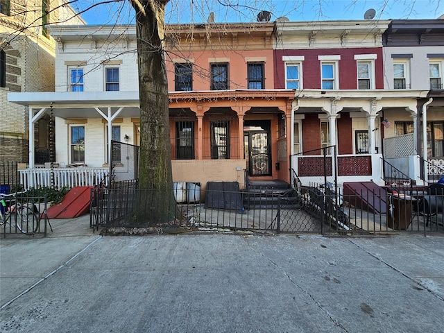 townhome / multi-family property with brick siding, a porch, and fence