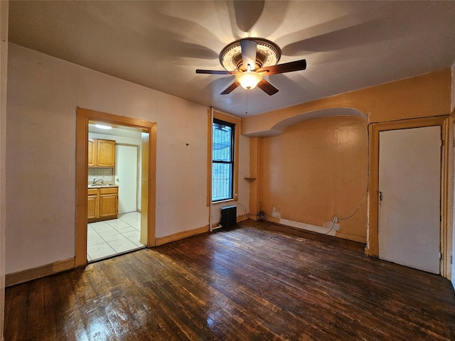 spare room with a sink, baseboards, hardwood / wood-style floors, and ceiling fan