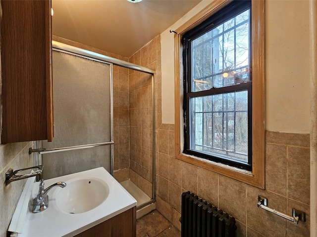 full bathroom with a wealth of natural light, radiator, tile walls, and a stall shower