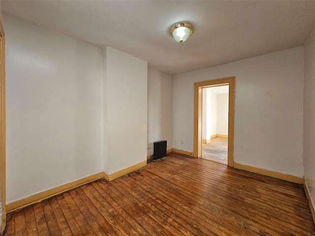 spare room featuring radiator heating unit, baseboards, and hardwood / wood-style floors