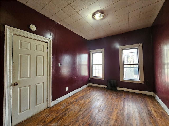 unfurnished room with radiator, baseboards, and dark wood-style flooring