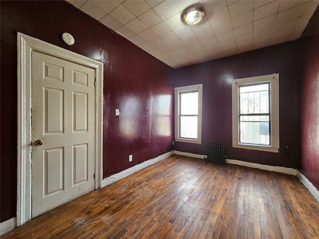 unfurnished room with radiator, baseboards, and hardwood / wood-style floors