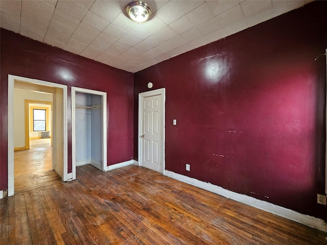 unfurnished bedroom featuring baseboards, wood-type flooring, and a closet