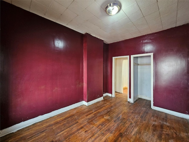 unfurnished bedroom with hardwood / wood-style floors, baseboards, and a closet