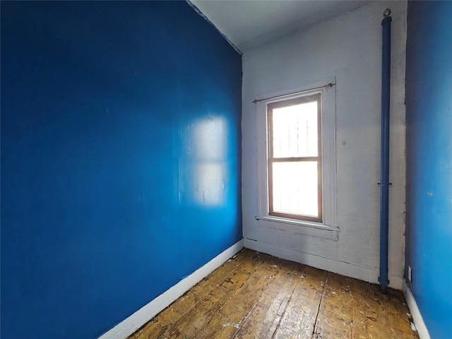 unfurnished room with baseboards and wood-type flooring