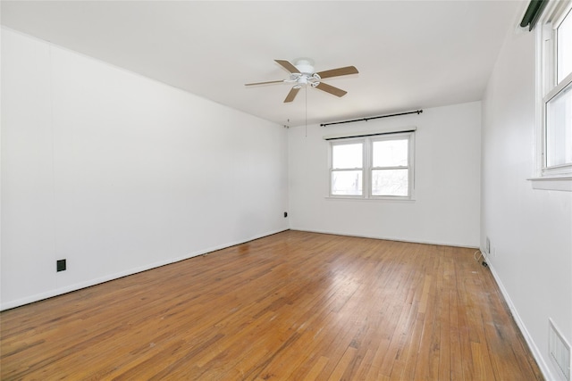 empty room featuring light wood-type flooring, baseboards, visible vents, and a ceiling fan