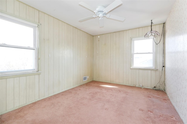 unfurnished room featuring plenty of natural light, ceiling fan, visible vents, and carpet floors