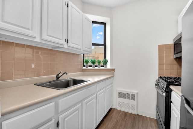 kitchen with visible vents, a sink, stainless steel microwave, white cabinets, and black range with gas stovetop