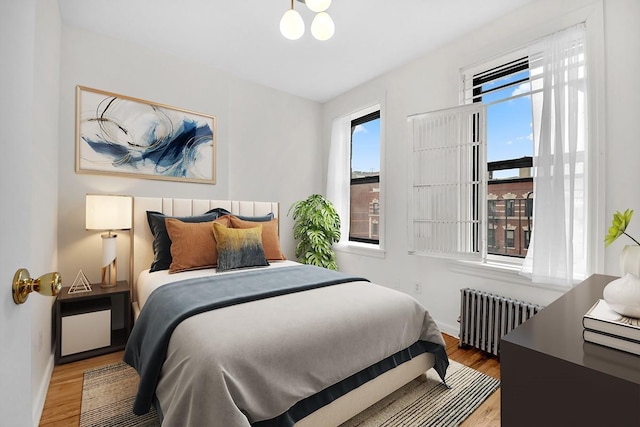 bedroom with radiator, baseboards, and wood finished floors