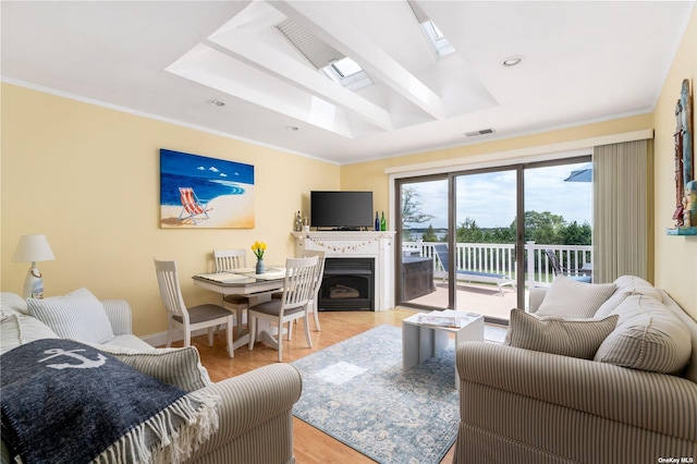 living room with a skylight, a fireplace, visible vents, and ornamental molding