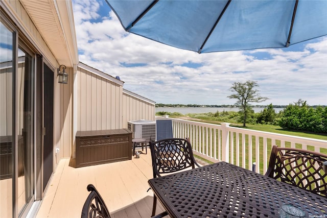 exterior space with outdoor dining space, central air condition unit, and a deck with water view