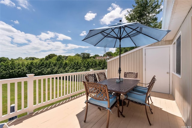 deck featuring outdoor dining space and a yard