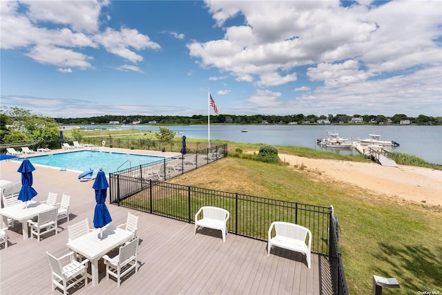 community pool featuring a lawn, fence, a boat dock, and a water view