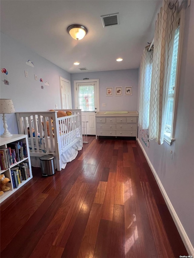 hallway featuring visible vents, baseboards, and hardwood / wood-style flooring