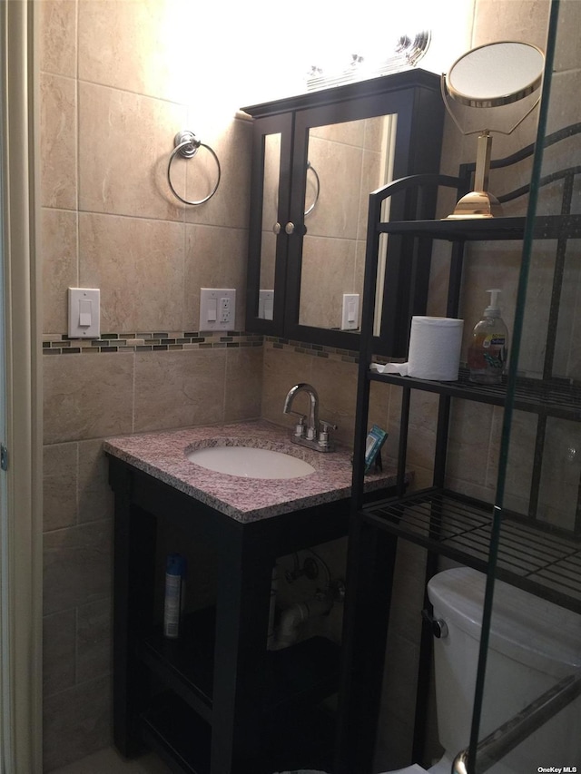 half bath with tasteful backsplash, toilet, tile walls, and vanity