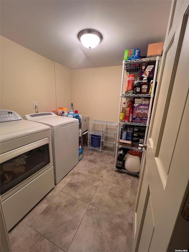 clothes washing area featuring separate washer and dryer, light tile patterned flooring, and laundry area