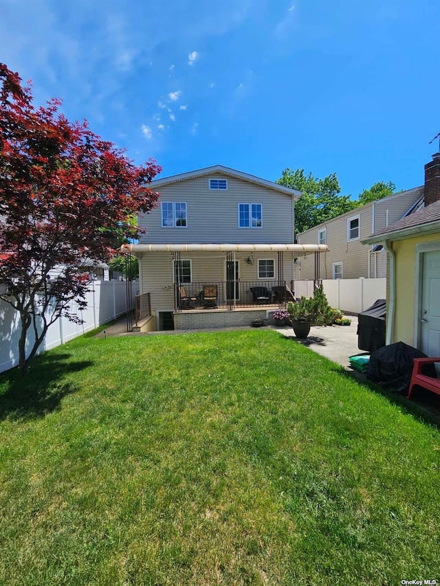 back of property with a patio area, a lawn, and a fenced backyard