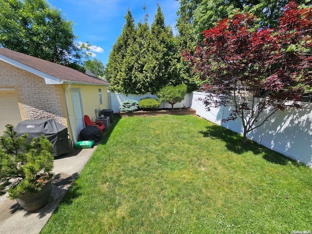 view of yard with a garage and a fenced backyard