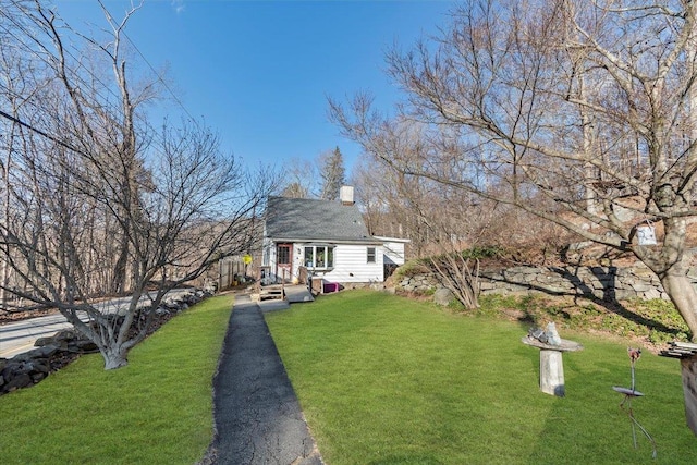 exterior space featuring driveway, a chimney, and a front yard