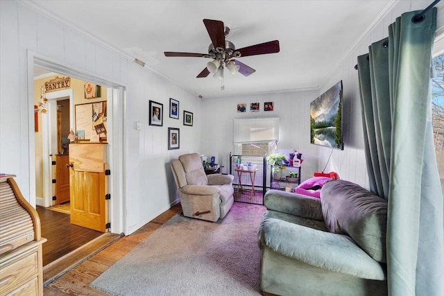 living room featuring a ceiling fan, crown molding, wood finished floors, and baseboards